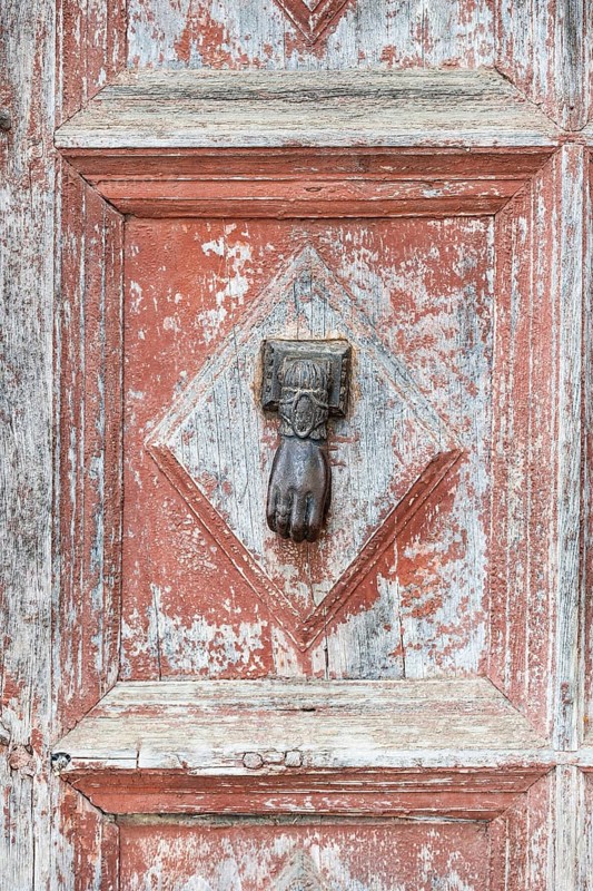 Old door with door knocker in shape of a hand
