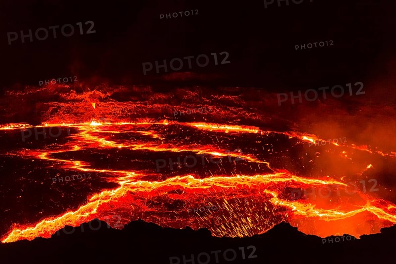 Glowing lava lake with eruptions at night