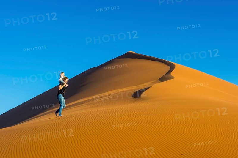 Woman with her baby walking up the giant sanddune Dune 45
