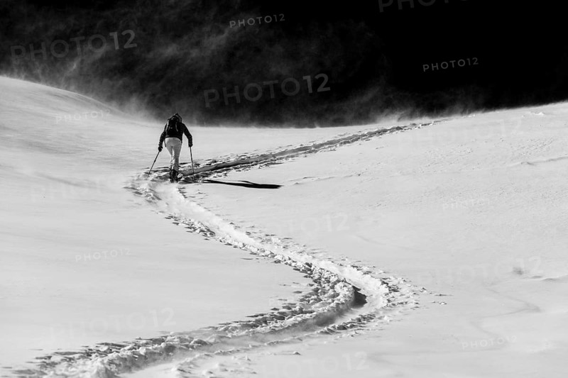 Ski mountaineer in winter landscape against a dark background