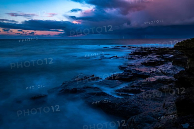 Rocky coast with dramatic dark clouds at sunset