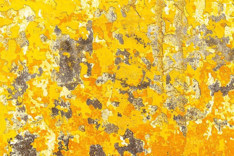 Crumbling plaster on yellow house wall