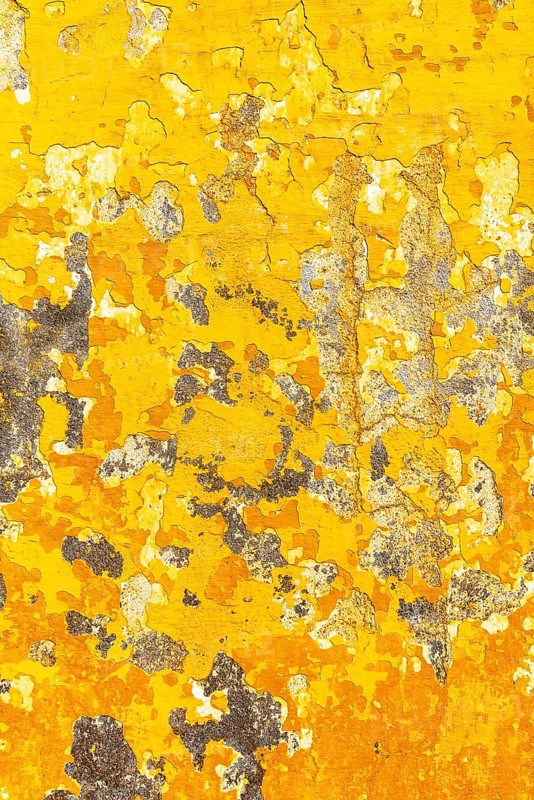 Crumbling plaster on yellow house wall