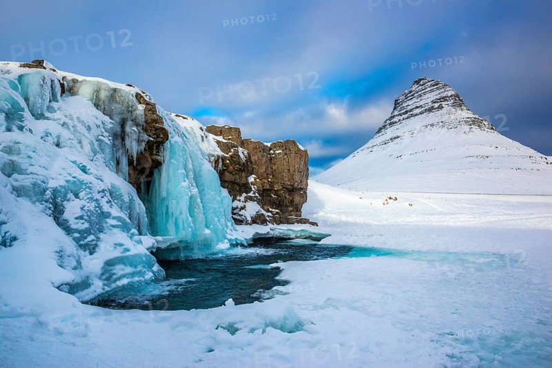 Frozen waterfall Kirkjufellsfoss and the mountain Kirkjufell with snow