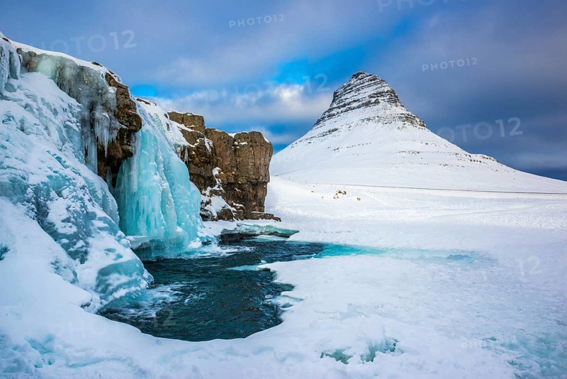 Frozen waterfall Kirkjufellsfoss and the mountain Kirkjufell with snow