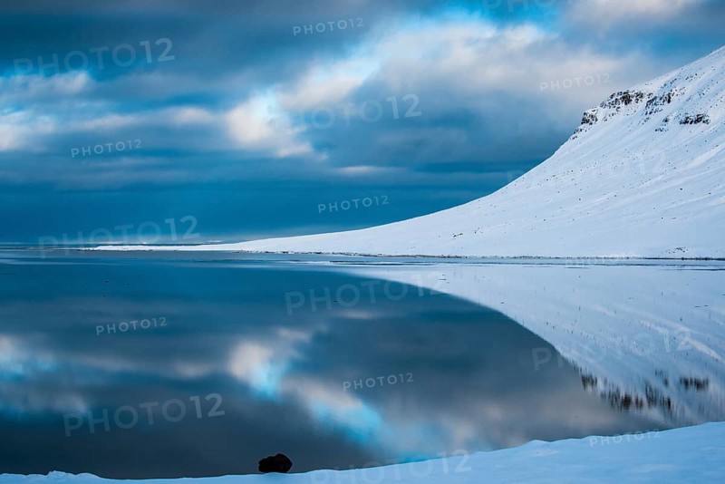 Snow-covered coastal landscape with water reflection