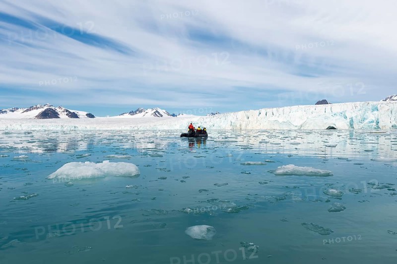 Zodiac boat with tourists navigating in front of Lilliehook glacier