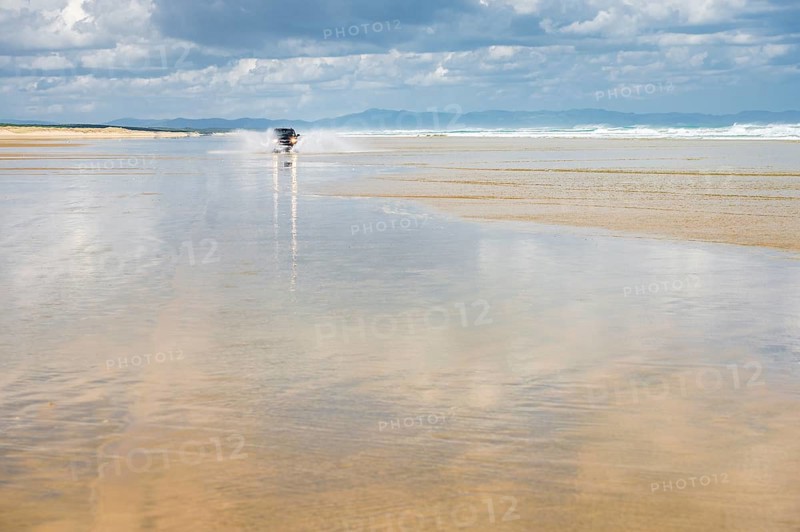 Black Hyundai Santa Fe 4x4 off-road vehicle drives on the sandy beach of Ninety Mile Beach in the water