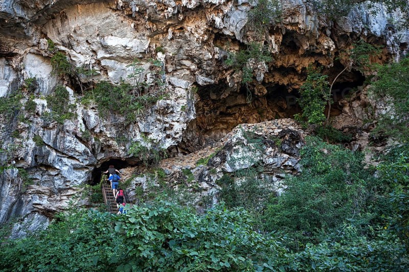 Tourists climbing into a cave in a karst cone called mogote