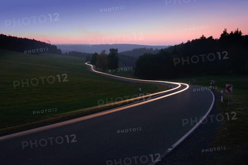 Car driving on winding country road in the evening
