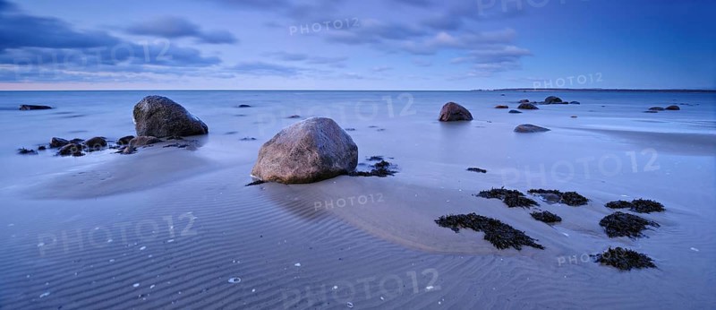 Sandy beach beach with large boulders and seaweed