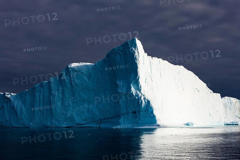 Iceberg under dark cloud sky