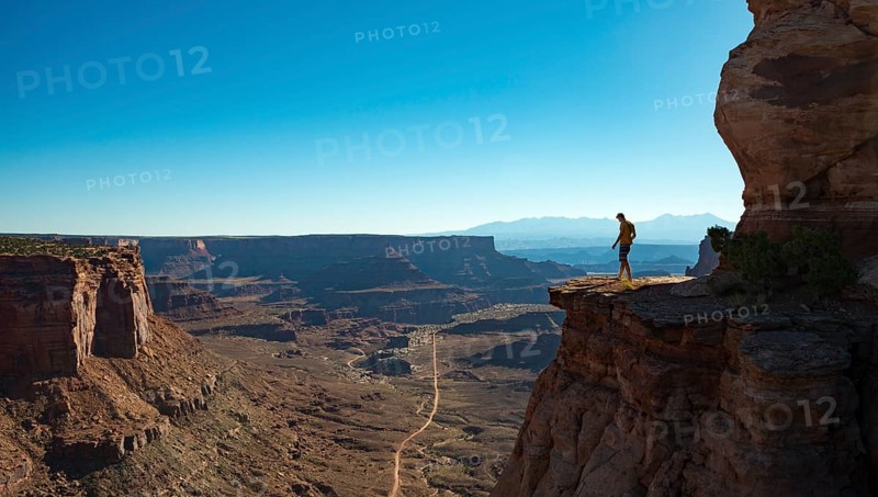 Young man standing at the edge of a fur cliff over Shafer Canyon Road