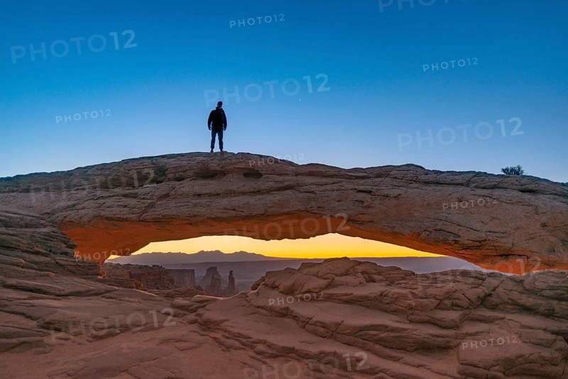 Young man standing on rock arch