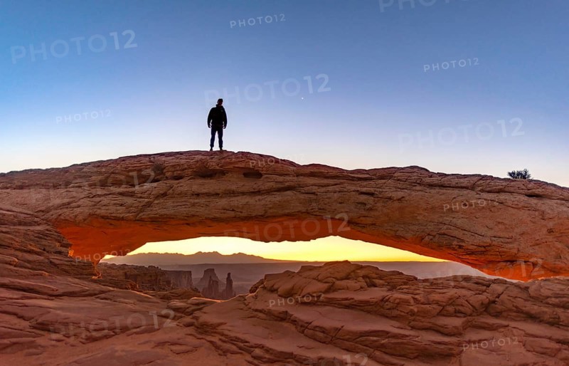 Young man standing on rock arch