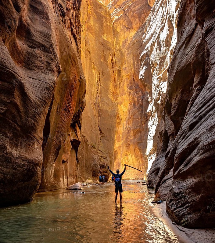 Hiker walks in the water and stretches arms into the air