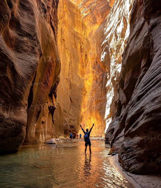 Hiker walks in the water and stretches arms into the air