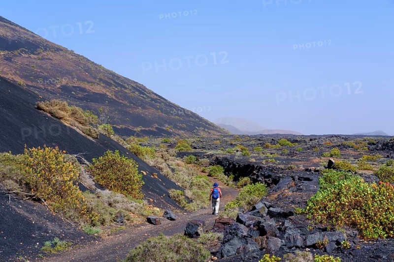 Woman walks on hiking trail through lava field
