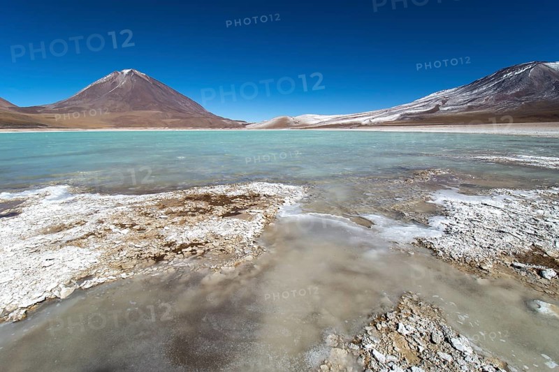 Laguna verde with deposits of borax on the shore and snow on the mountains