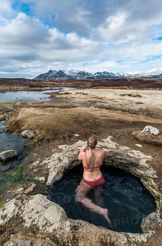 Young woman in hot spring looking towards mountains