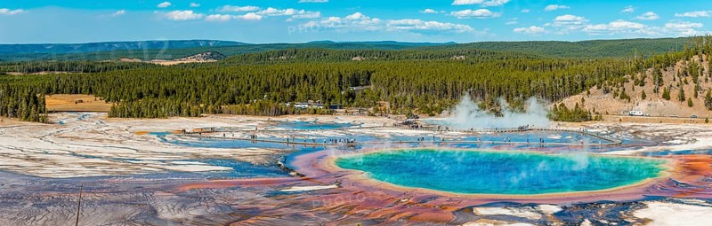 Visitors on footbridge over steaming hot spring with coloured mineral deposits