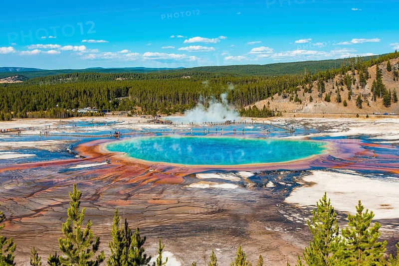 Visitors on footbridge over steaming hot spring with coloured mineral deposits