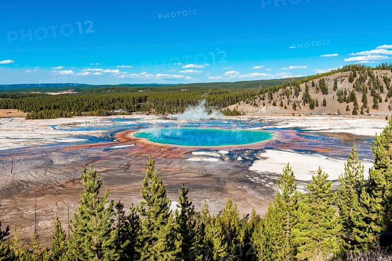 Visitors on footbridge over steaming hot spring with coloured mineral deposits