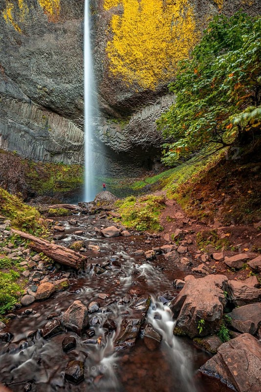 Man at waterfall in front of basalt rock