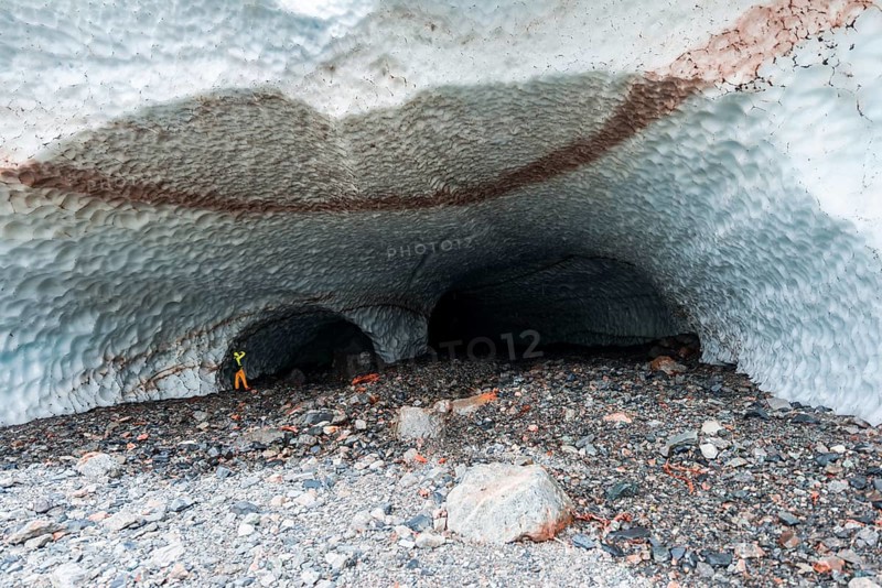 Man at the entrance of an ice cave of a glacier