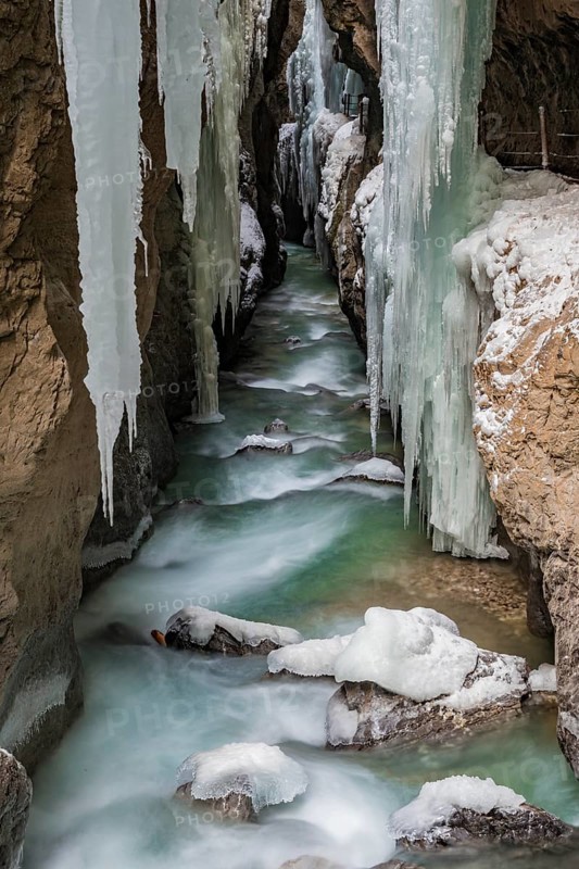 Path to Partnach wild river in the Partnach gorge with long icicles and snow in winter