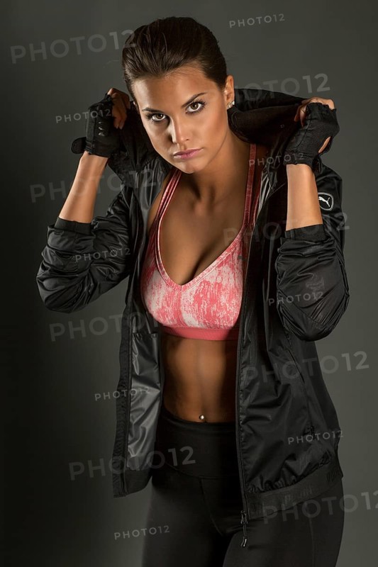 Portrait of a young woman with dark hair tied together in a sporty outfit