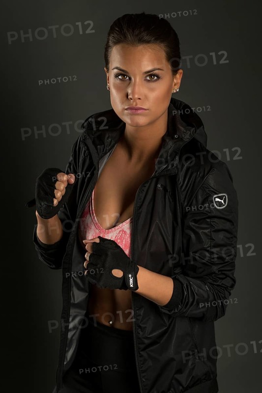 Portrait of a young woman with dark hair tied together in a sporty outfit