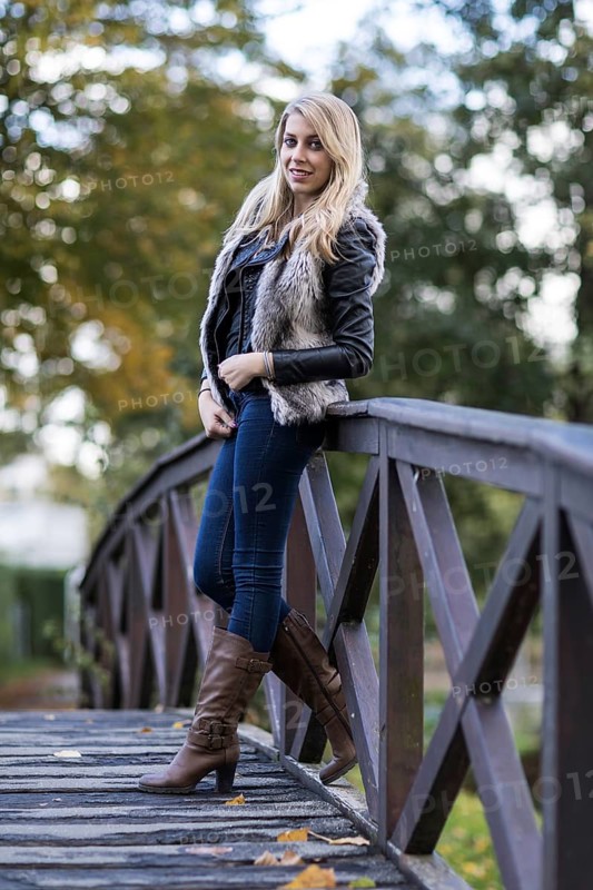 Young blonde woman poses on wooden bridge