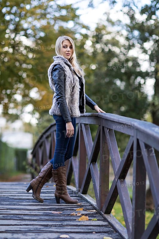 Young blonde woman poses on a wooden bridge