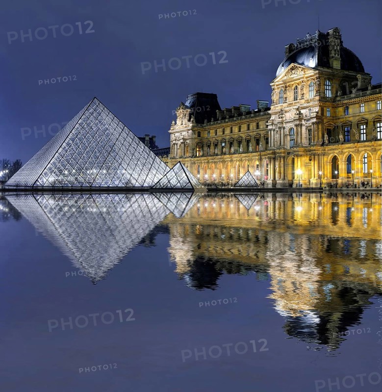 Illuminated Louvre with glass pyramid with reflection in the water