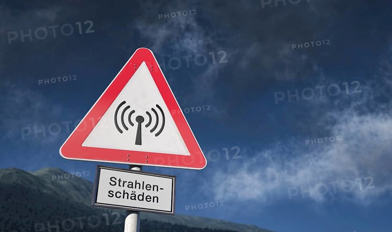 Warning sign against blue sky with clouds