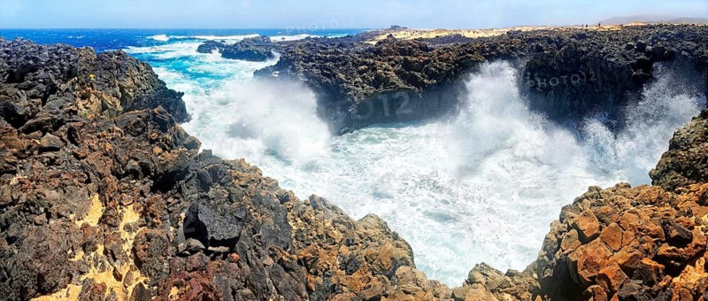 Surf on black basalt cliffs