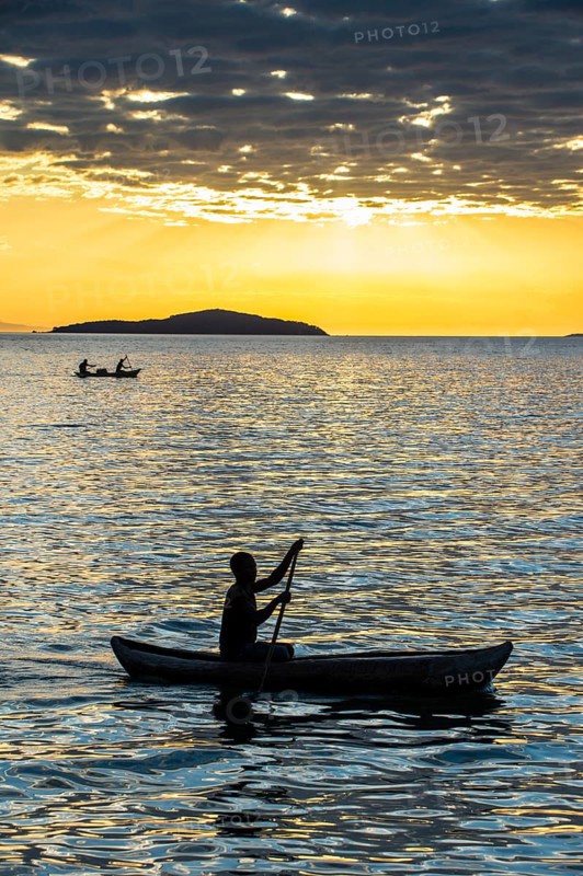Man in a little fishing boat at sunset