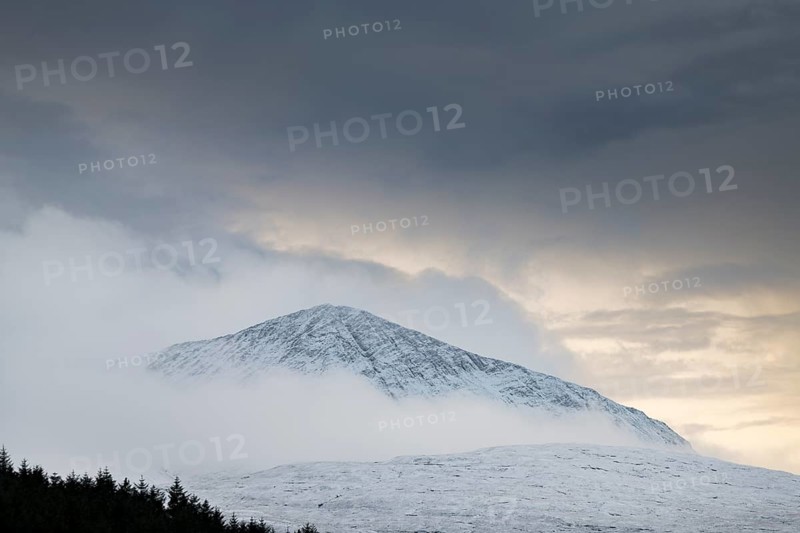 Snow-covered mountain top with clouds in snow-covered landscape