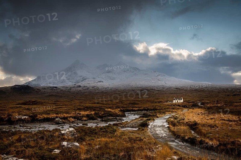 Waterfall of AltDearg Mor with snowy peaks of Marsco and Sgurr Nan Gillean and small house