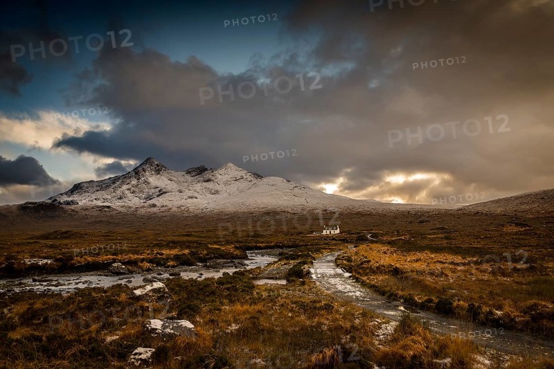 Waterfall of AltDearg Mor with snowy peaks of Marsco and Sgurr Nan Gillean and small house