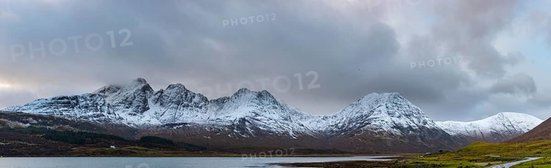 Loch Slapin with small house in Highland landscape with snowy Cullin mountains in the background
