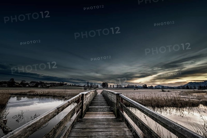 Holzsteg over the Ach with reflection and dramatic sky