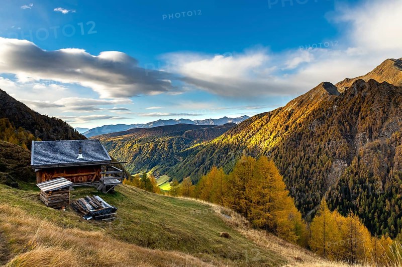 Mountain hut over valley with autumnal mountain larch forest (Larix decidua)