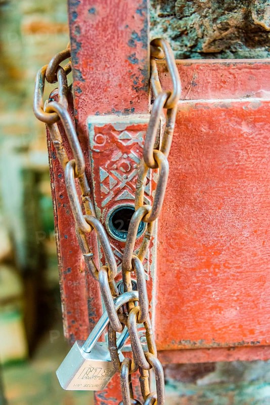 Padlock with iron chain hanging on a door
