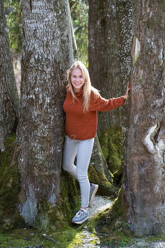 Young woman with long blond hair between trees