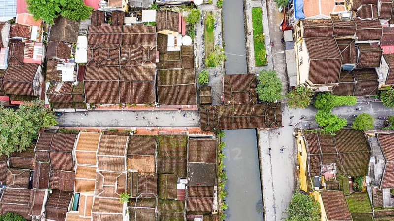 Roofs of old houses with Japanese Covered Bridge or Cau Chua Pagoda in Hoi An ancient town