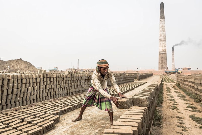 Workers of a brickyard stacking dried bricks
