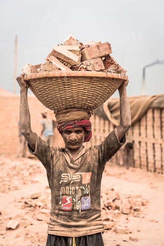 Brickyard worker carrying bricks in a basket on his head