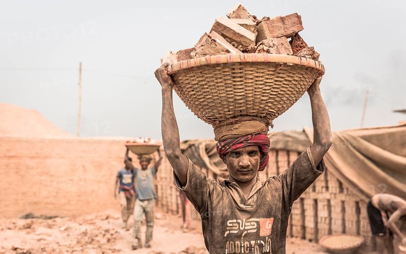 Brickyard worker carrying bricks in a basket on his head